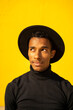 © VISTA by Westend61 - Portrait of young man, wearing black in front of yellow wall, looking up