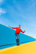 © VISTA by Westend61 - Young man with headphones, listening music, dancing on yellow wall