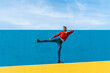 © VISTA by Westend61 - Young man with headphones, listening music, dancing on yellow wall