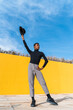 © VISTA by Westend61 - Young man with black hat, dancing in front of yellow wall