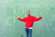 © VISTA by Westend61 - Portrait of angry young man wearing red sweatshirt in front of green wall