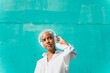 © VISTA by Westend61 - Woman in front of teal wall, wearing headphones