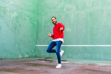 Portrait Of Bearded Young Man Dancing In Front Of Green Wall