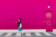 © VISTA by Westend61 - Young woman walking along pink wall, using smartphone