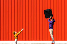 Young Man And Woman Performing With A Box In Front Of A Red Wall