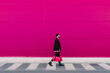 © VISTA by Westend61 - Young man walking with travelling bag in front of a pink wall
