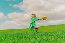Happy Young Woman Wearing Green Dress Jumping In The Air On A Field