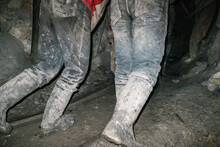 Detail Of The Boots Of Two Miners Pushing A Wagon In A Tunnel In