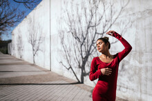 Woman In Red Dress With Dancer Pose And Tree Shadows On  Wall