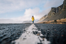 Iceland, Woman Walking On Median Strip Of Country Road