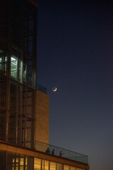 Sticker - Crescent moon in the night sky next to a building