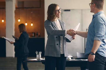 Beautiful business woman shaking hands with business man at the office 