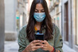 © Bisual Photo - Woman wearing a protective mask on her face while using mobile phone in the street