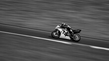 A Monochrome Panning Shot Of A Racing Bike Cornering On A Track