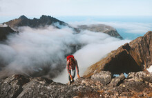 Hiker Man Climbing On Mountain Top Above Clouds Travel Hiking With Backpack Outdoor Extreme Adventure Vacation Active Healthy Lifestyle Trekking In Norway