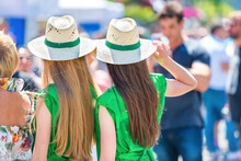 Two Young Women In Green Gress With Long Blond Hair And Crowd Of People