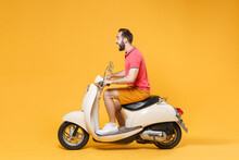 Side View Of Shocked Young Bearded Man Guy In Casual Summer Clothes Driving Moped Isolated On Yellow Wall Background Studio Portrait. Driving Motorbike Transportation Concept. Mock Up Copy Space.