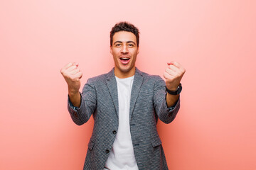 Wall Mural - young arabian man celebrating an unbelievable success like a winner, looking excited and happy saying take that! against pink wall