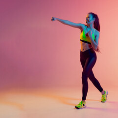 Cute girl fitness instructor teaches Boxing or body combat online training remotely on a bright neon background.