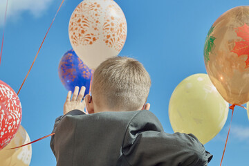 back to school September 1 a boy waves and balloons against a blue sky