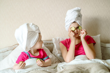 Wall Mural - Beautiful girl with facial mask of cucumber. face mask, children laugh, funny faces, first makeup for a teenager.Morning in bed after bath. white towel.