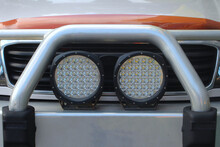 Pair Round Black LED Driving Lights And Bull Bar On The Front Of A Four Wheel Drive Vehicle.