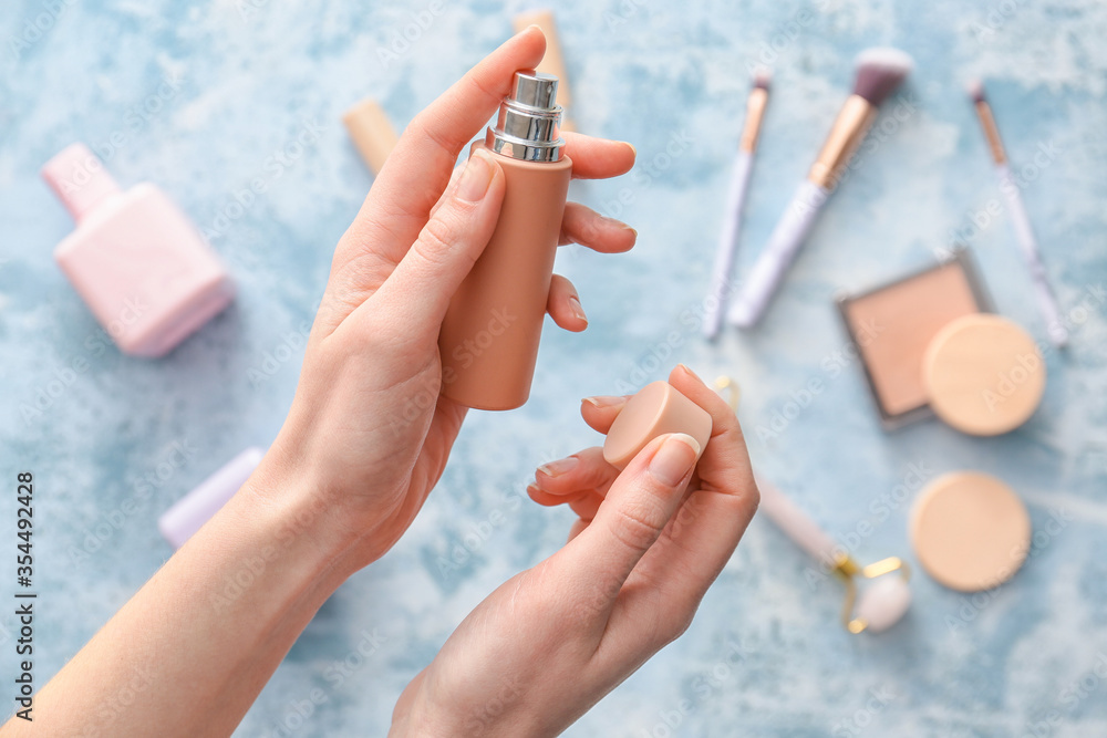 Female hands with perfume on color background