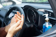 © doucefleur - woman applying hand sanitizer alcohol gel to clean her hand and before driving a car during covid-19 pandemic, new normal lifestyle concept background