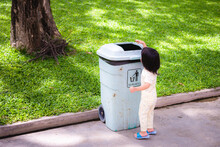 Asian Baby Little Girl Throwing Garbage Into Trash Can. Baby Age 2 - 3 Years Old.