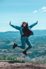 Poster - young pretty woman jumping at the top of the mountain