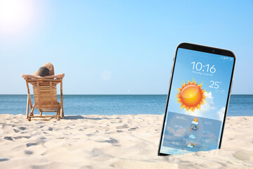 Wall Mural - young woman relaxing in deck chair on sandy beach and smartphone with open weather forecast app