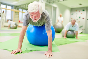 Senior auf Gymnastikball bei Rückentraining