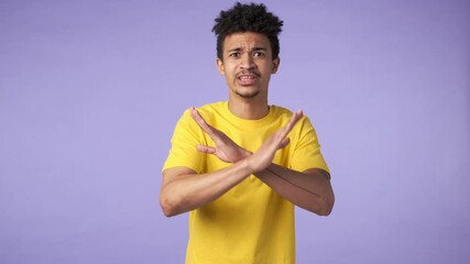 Sticker - Young african displeased guy isolated over purple background says no showing stop gesture