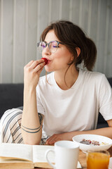 Sticker - Photo of woman reading book and eating strawberry while having breakfast