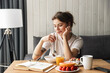 © Drobot Dean - Photo of young thinking woman reading book while having breakfast