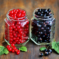 Canvas Print - Red and black currant in a glass jar on an old wooden background. Canning of berries. Planned to cook jam from the currant. Soft focus. Place for text.