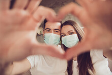 Closeup Photo Of Adorable Young Couple Lady Guy Spend Quarantine Together Stay Home Happy Making Arms Fingers Heart Sign Figure Sit Sofa Divan Wear Facial Medical Mask Room Indoors