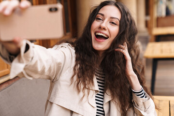 Wall Mural - Image of happy woman taking selfie photo on cellphone and smiling