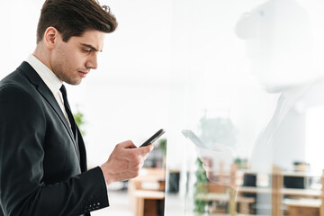 Sticker - Image of serious businessman wearing black suit using mobile phone