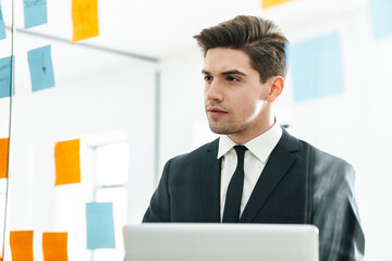 Sticker - Image of concentrated young businessman using laptop while working