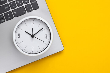 Wall Mural - Laptop and alarm clock on yellow background. Time running away. The concept of urgent deadlines at work and commitments. Top view. Flat lay