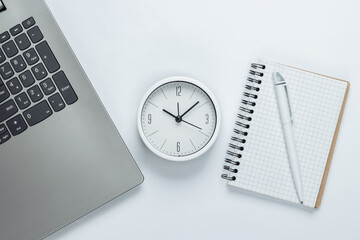 Wall Mural - Laptop, notebook and alarm clock on white background. The concept of urgent deadlines at work and commitments. Top view