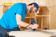 © stockphoto-graf - carpenter with hand wood router machine at work. closeup of routing  slot into plank of pine woodworking construction tool concept furniture making diy background