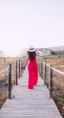 Woman walking along boardwalk towards sunset 