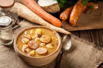 Canvas Print - Wooden bowl of split pea soup with sausage and potatoes