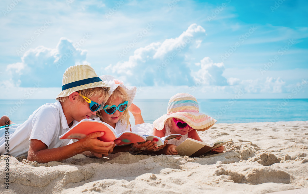 happy kids -boy and girls- read books on beach, summer reading on vacation - obrazy, fototapety, plakaty 