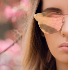 Wall Mural - Beautiful young blonde woman in stylish pink sunglasses in outdoor. Close-up photo.