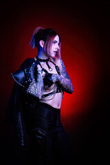 Wall Mural - Portrait of a young sexy tattooed cyberpunk woman wearing a studded leather jacket over her shoulder