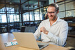 © Drobot Dean - Photo of handsome smiling man working with laptop while sitting