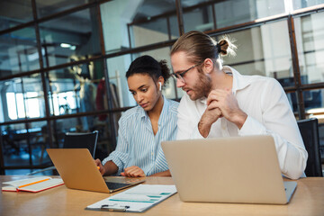 Photo of multinational focused colleagues working with laptops